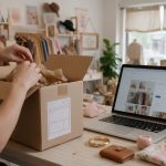 Boutique owner packing online store orders next to a laptop