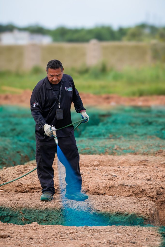 Pest control technician applying a pre-slab termite treatment at a new home site