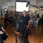 Video crew filming a business owner interview with camera and lighting